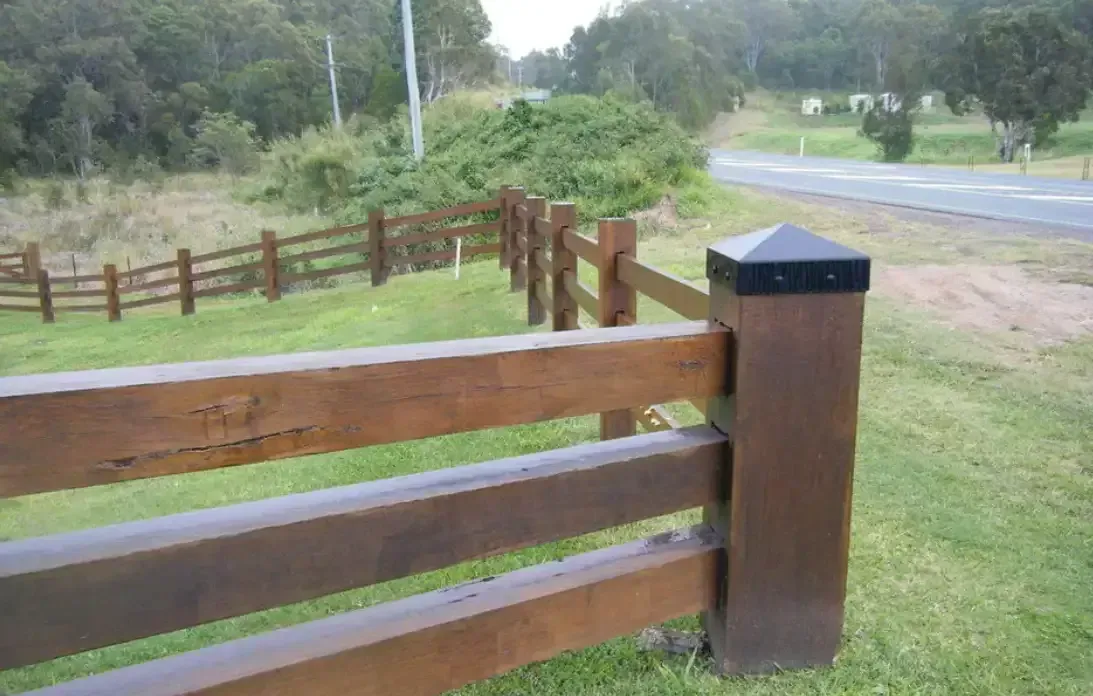 Wooden Fence With Dark Cap Posts Beside a Road and Green Grassy Area — Keith Dellit Rural Fencing in Yandina Creek, QLD 