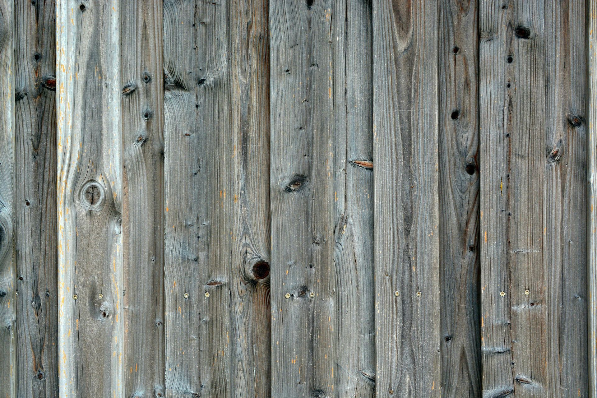 Weathered wooden planks, vertical lines, various shades of gray, knots, and aged appearance.