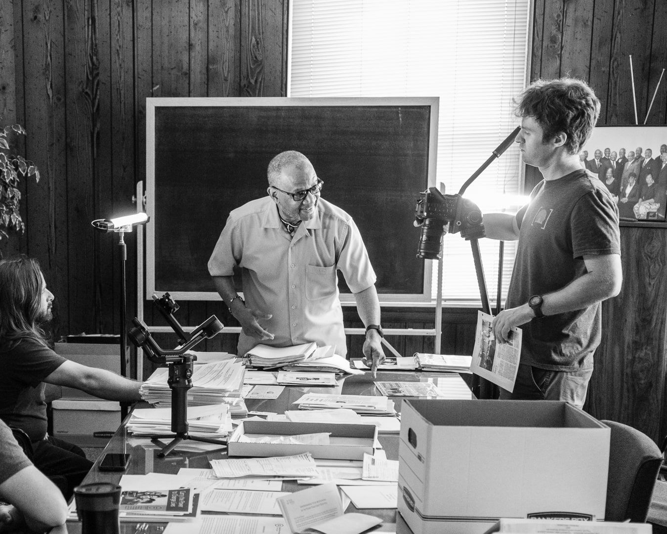 A black and white photo of a group of men around a table.