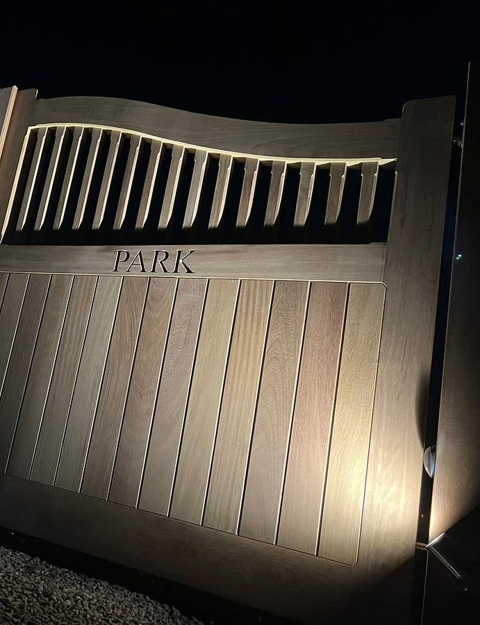 A pair of wooden gates are sitting in front of a brick wall.