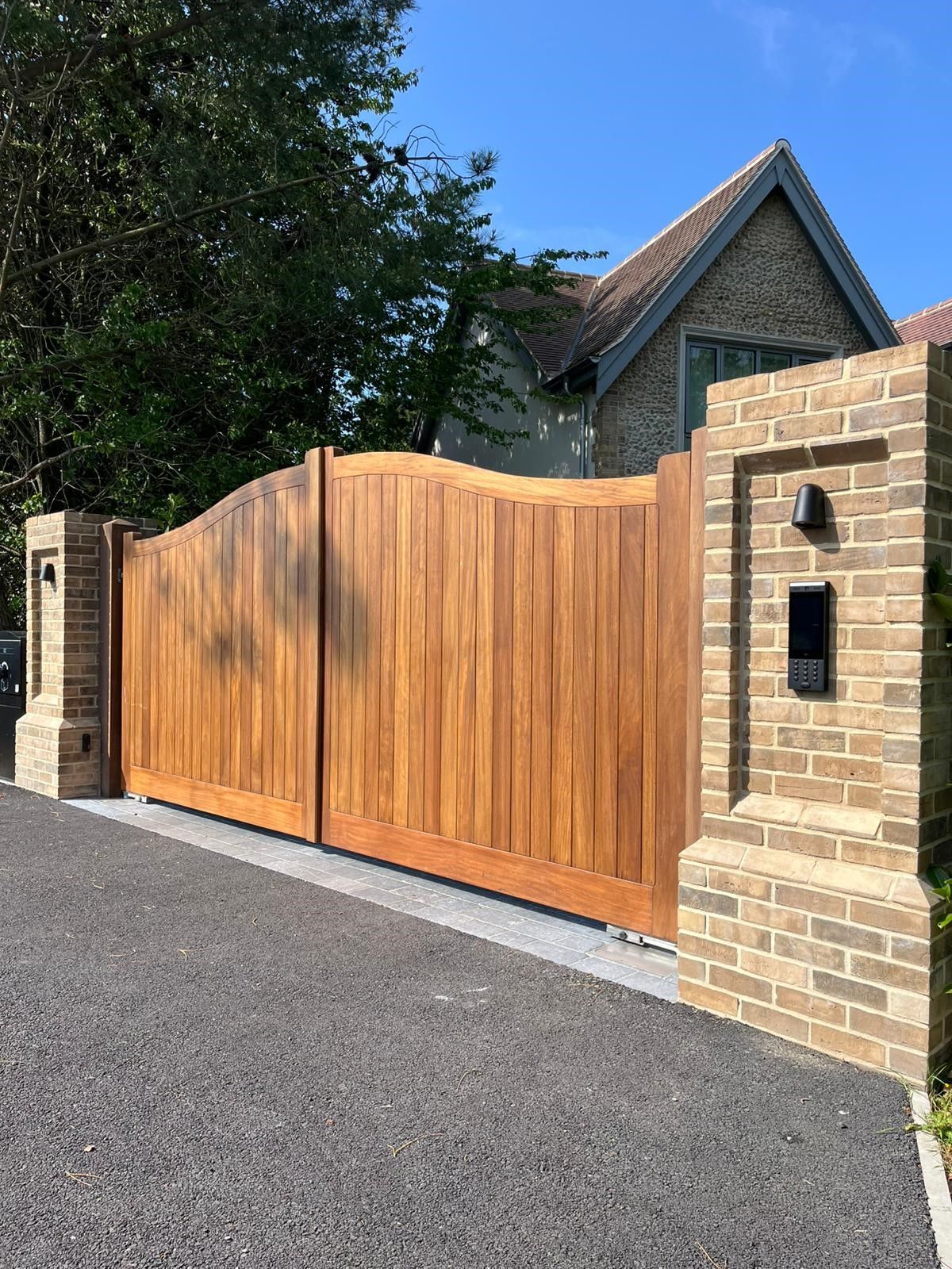A wooden gate is sitting on top of a brick driveway.