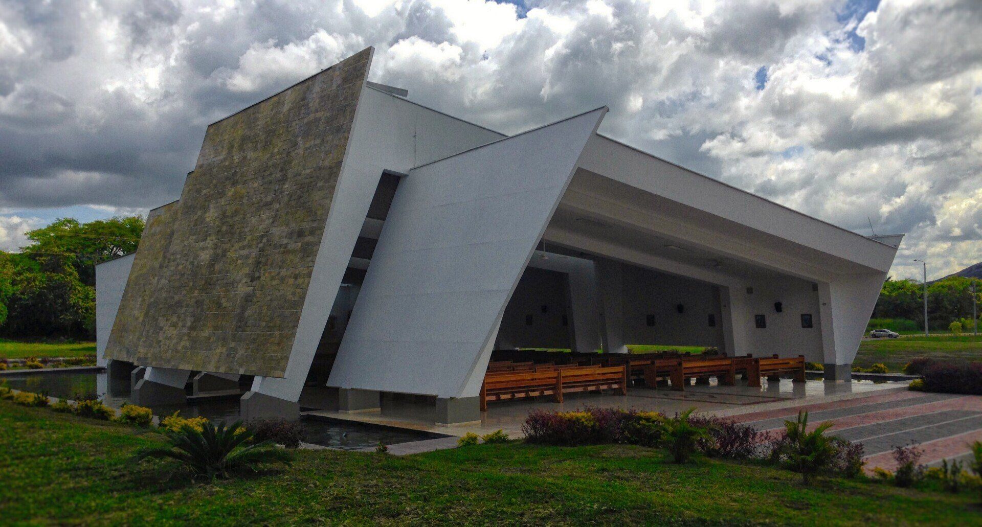Un edificio blanco con techo curvo está rodeado de hierba y árboles.
