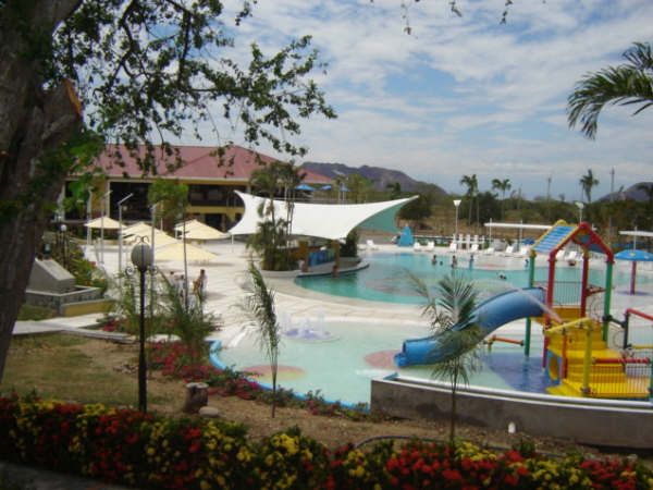 Una piscina con tobogán y una casa al fondo