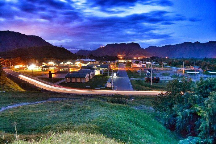 Una vista de un pequeño pueblo por la noche con montañas al fondo