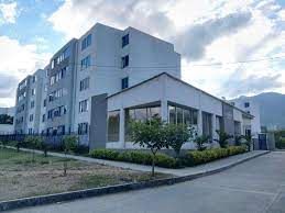 Un gran edificio blanco con muchas ventanas y árboles frente a él.