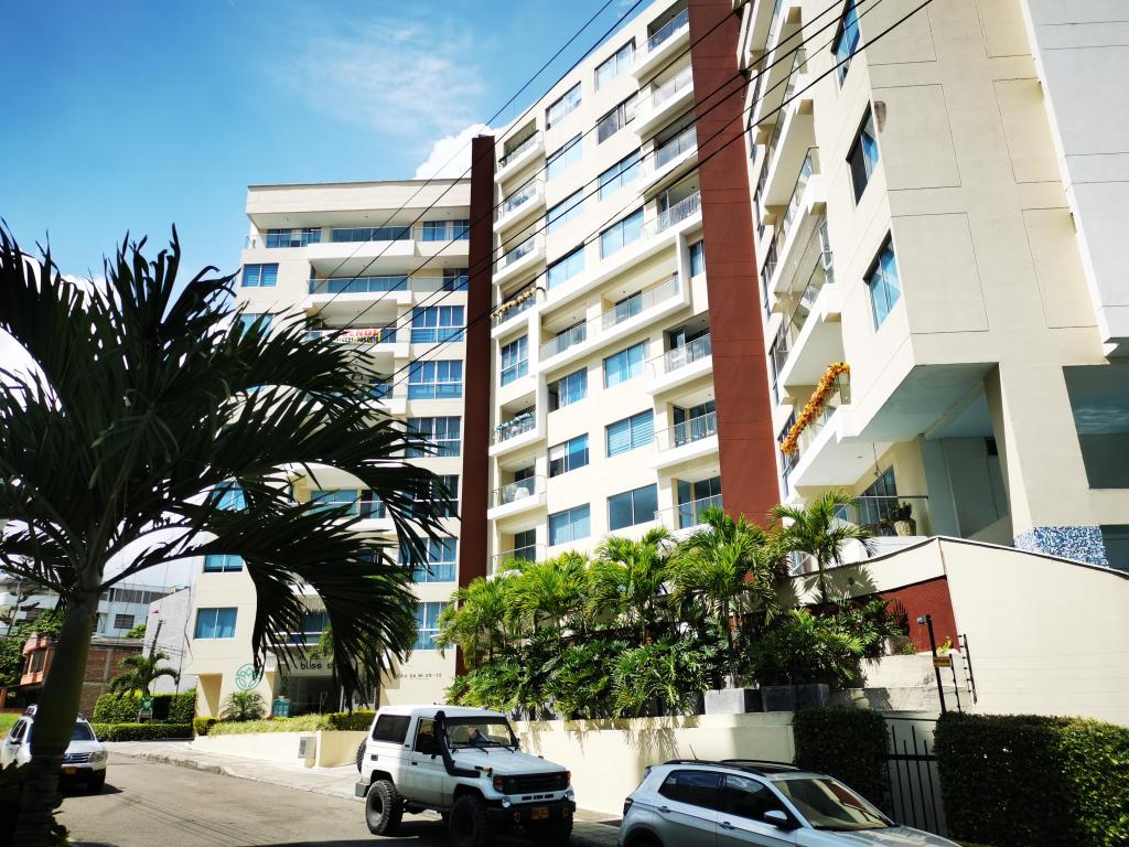 Un todoterreno blanco está estacionado frente a un edificio alto