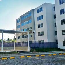 Un gran edificio blanco con muchas ventanas se encuentra al lado de un estacionamiento.