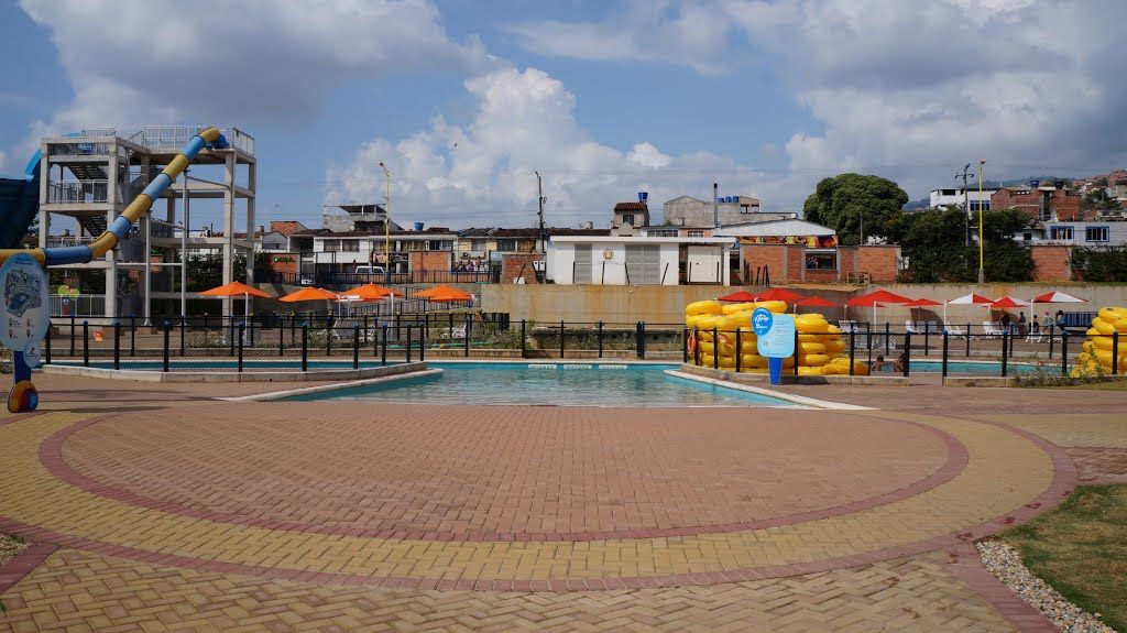 Una gran piscina está rodeada por una pasarela de ladrillos en un parque.
