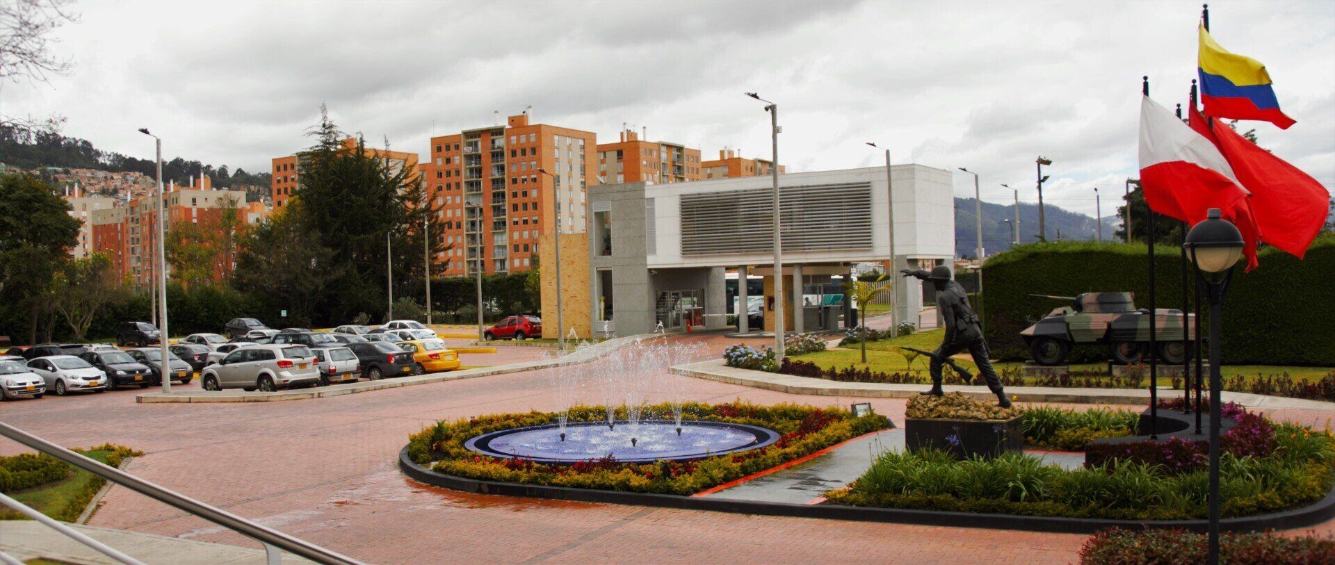 Un parque con una fuente y banderas frente a un edificio