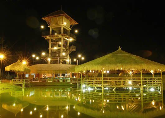 Una piscina con una torre al fondo por la noche.