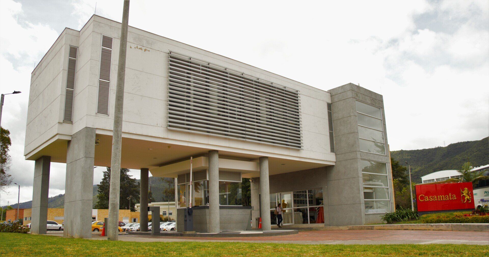 Un gran edificio blanco con un cartel rojo delante