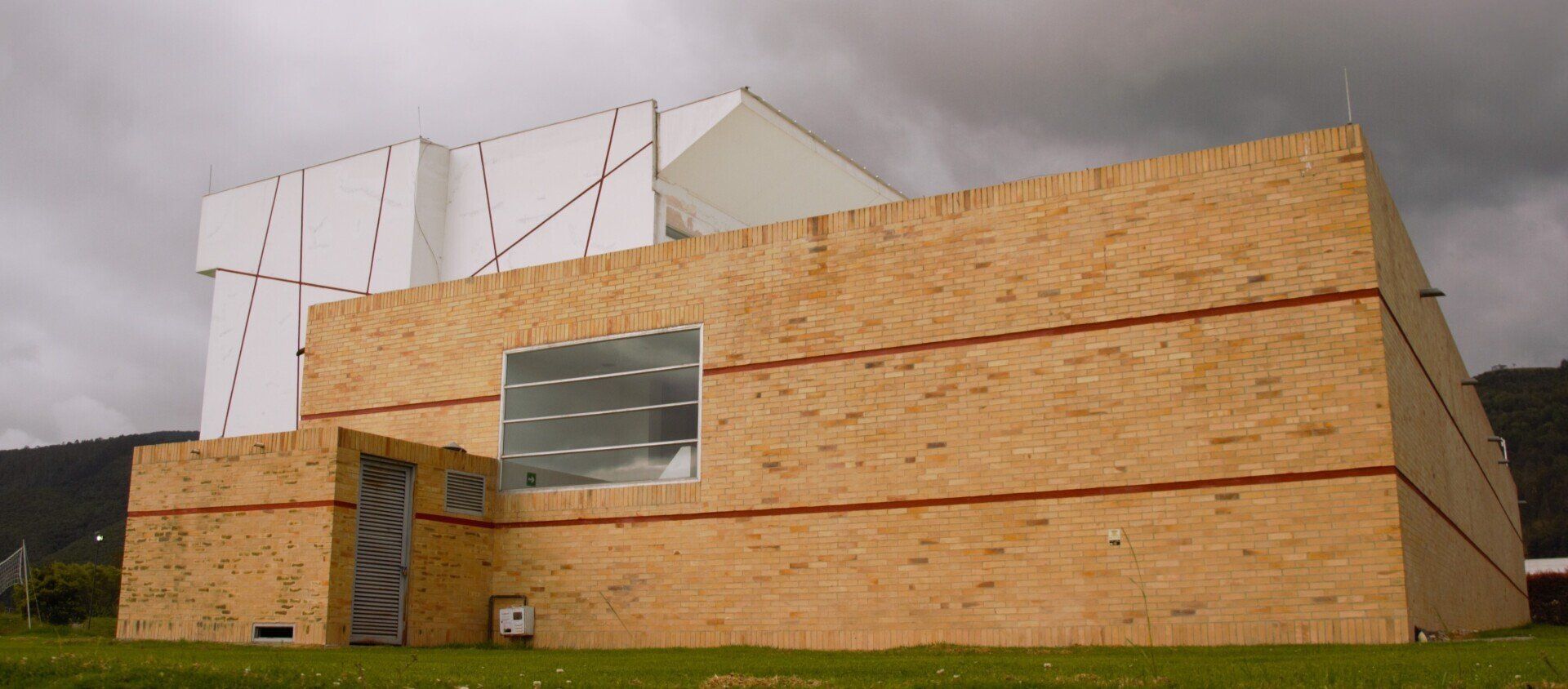 Un gran edificio de madera se encuentra en lo alto de un exuberante campo verde.