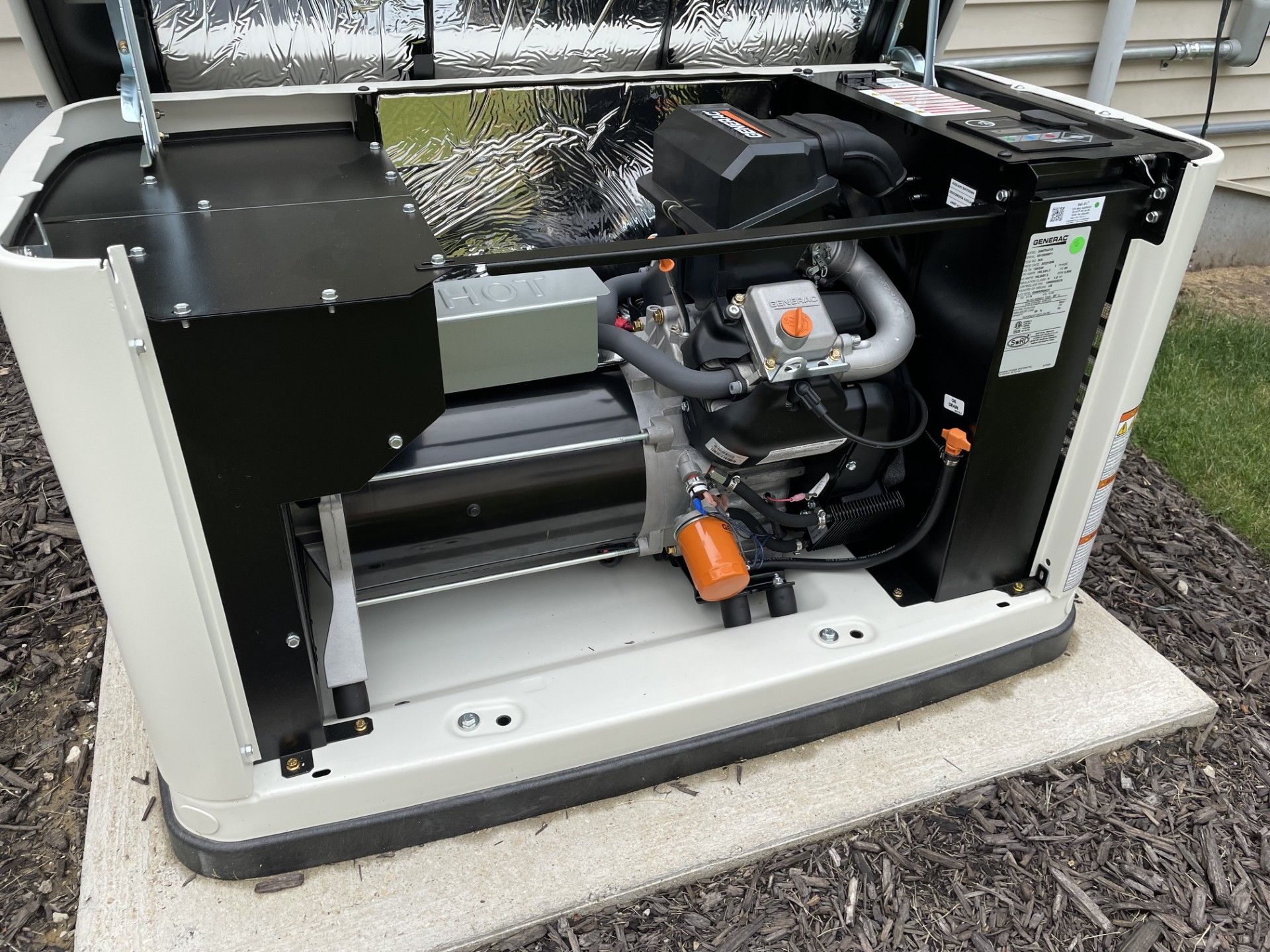 Generator with open lid, showing engine components and electrical workings. Beige unit on concrete base.