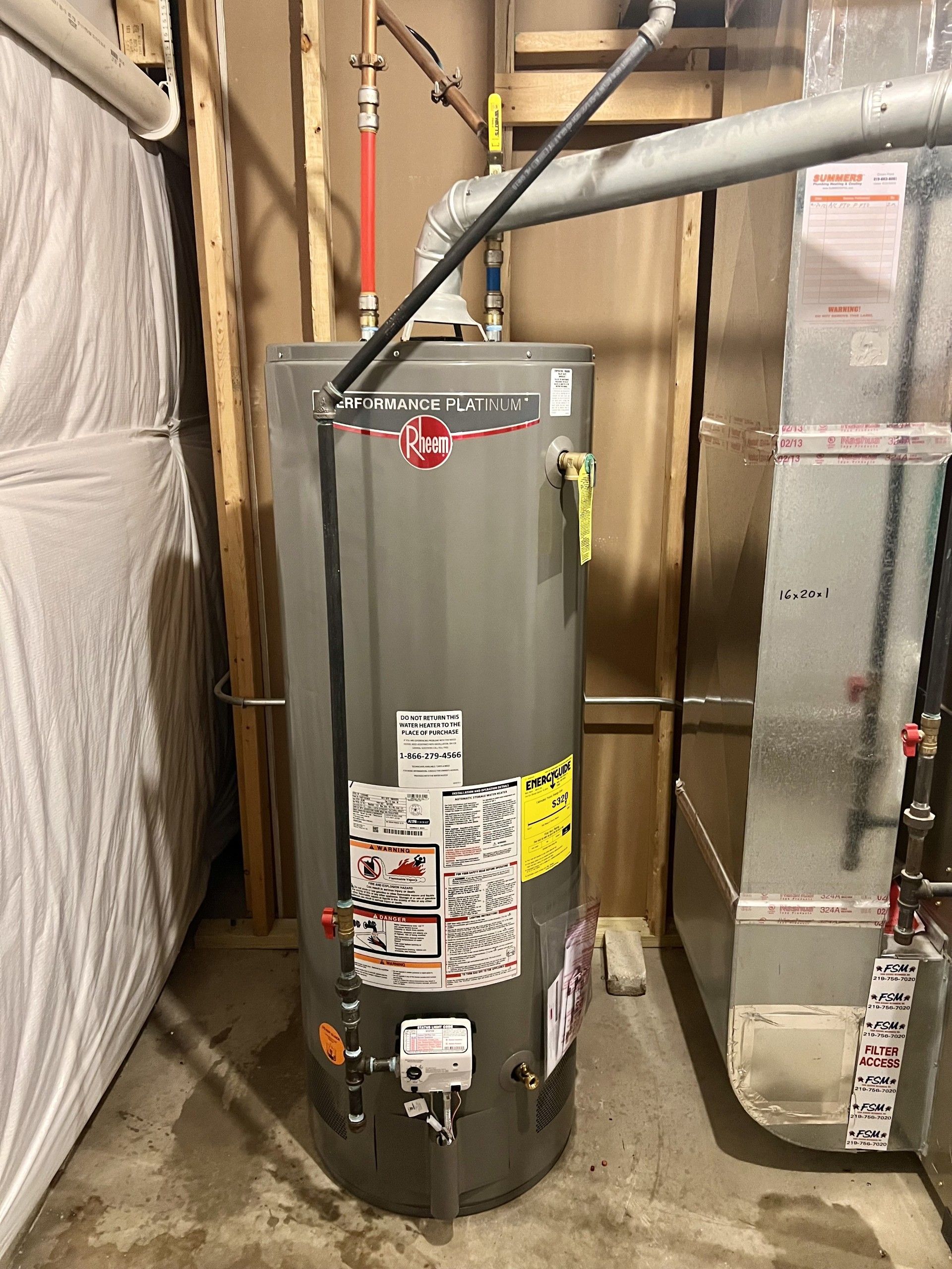 Gray water heater in a utility room next to HVAC system. Copper and gray pipes are visible.