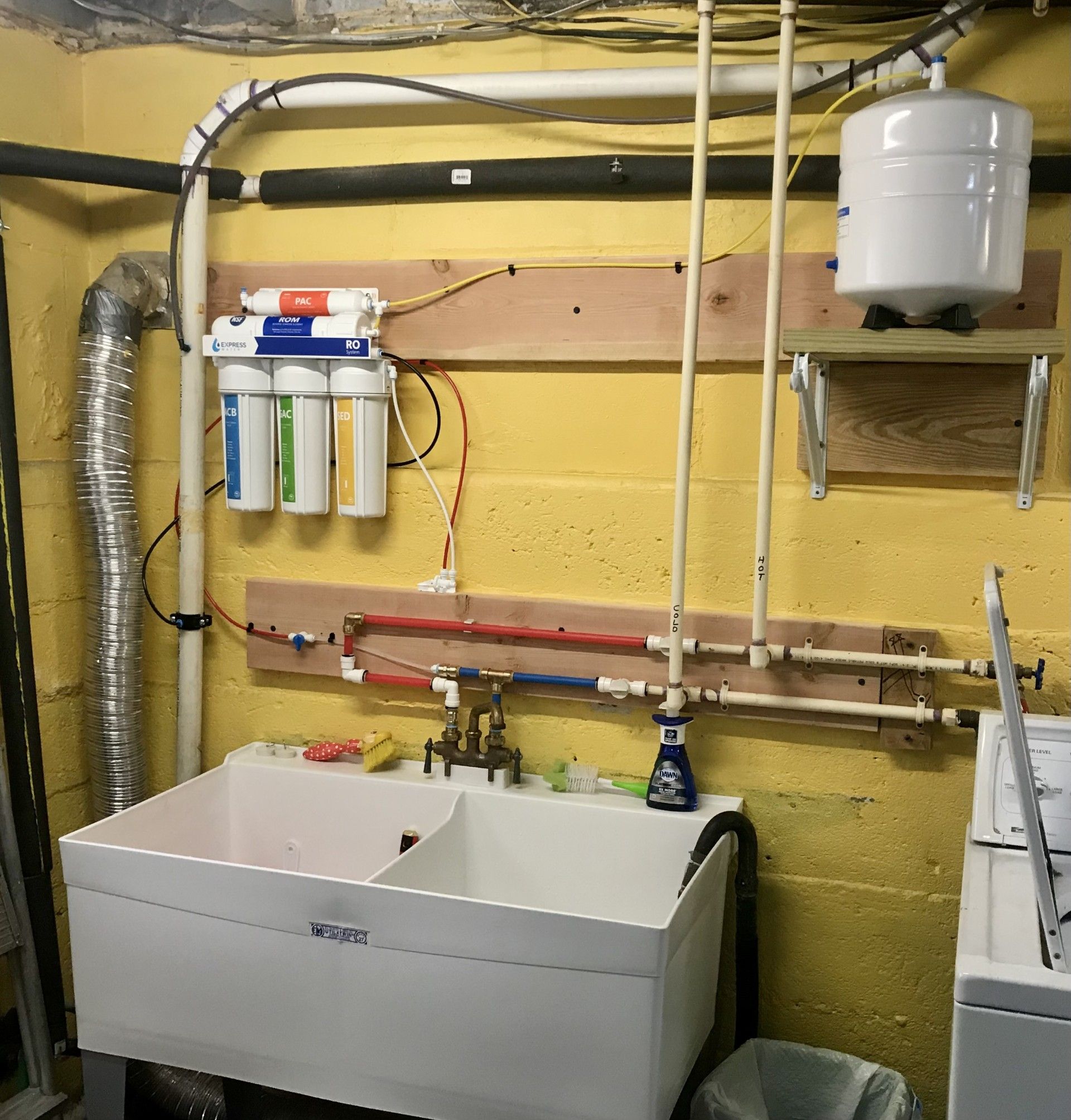 Laundry room with a utility sink, water filtration system, and a hot water tank.