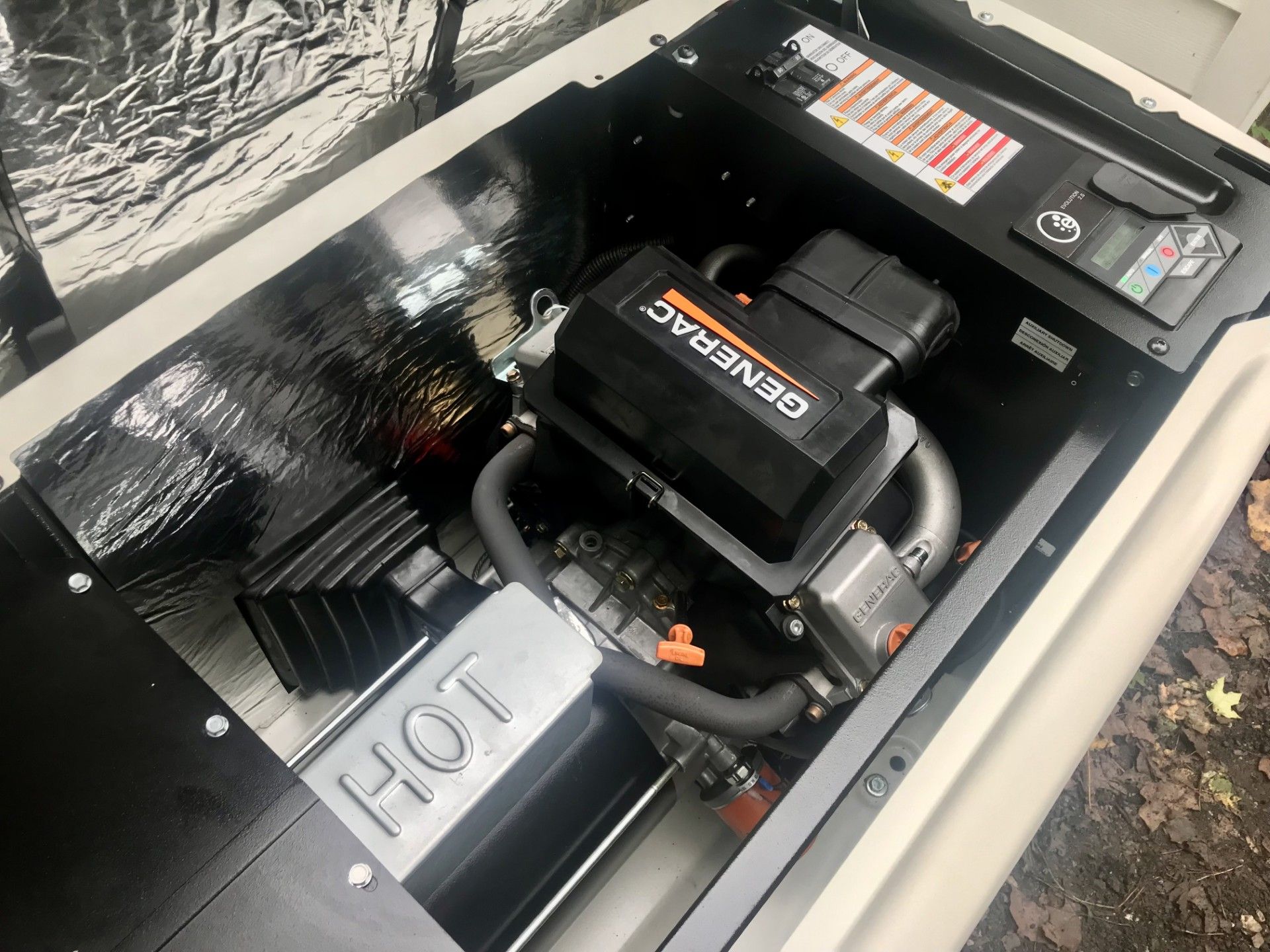 Generac home generator. Open compartment reveals engine, control panel, and heat-resistant insulation.