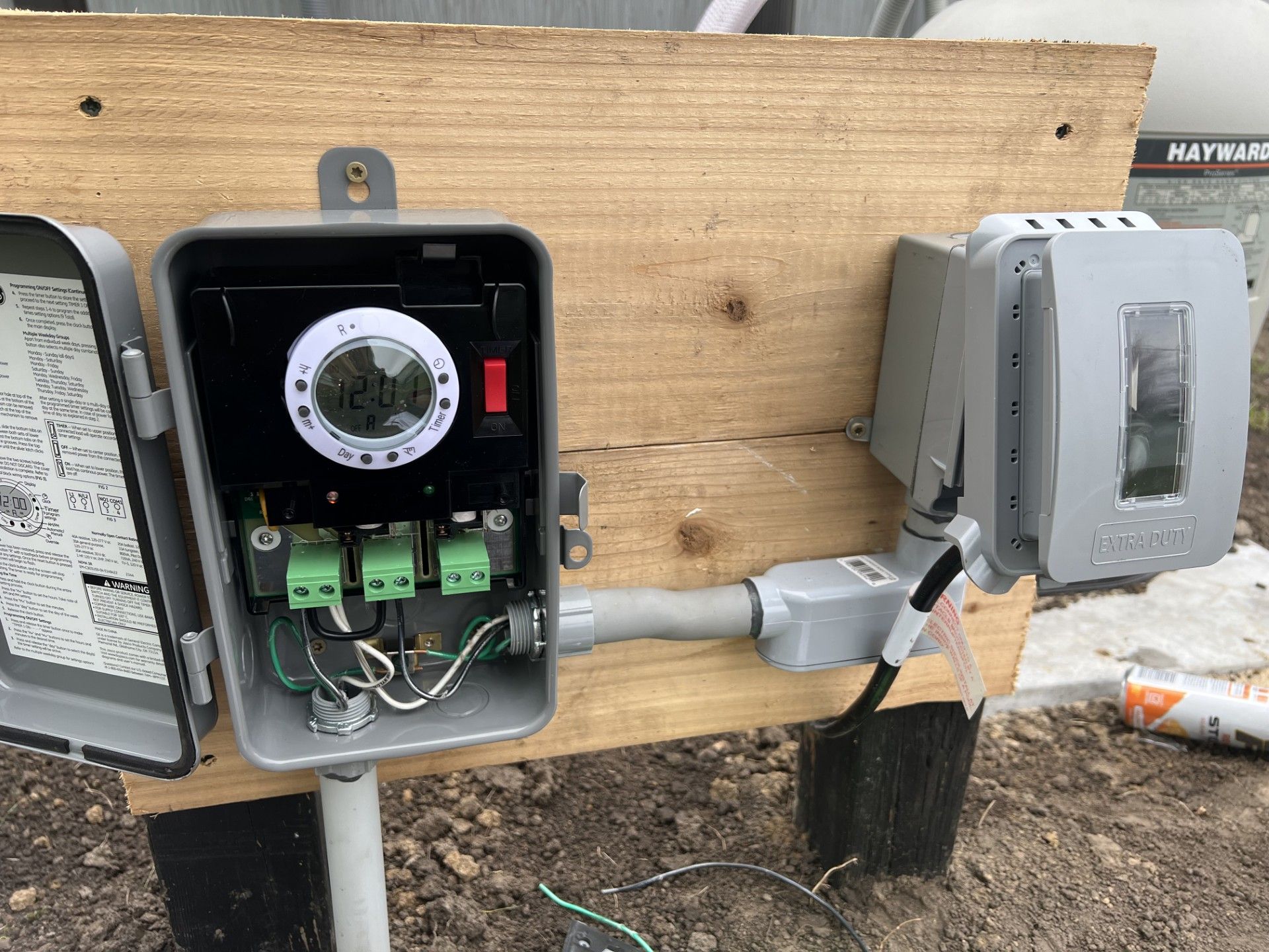 Outdoor electrical timer box with wiring and a connected control box.