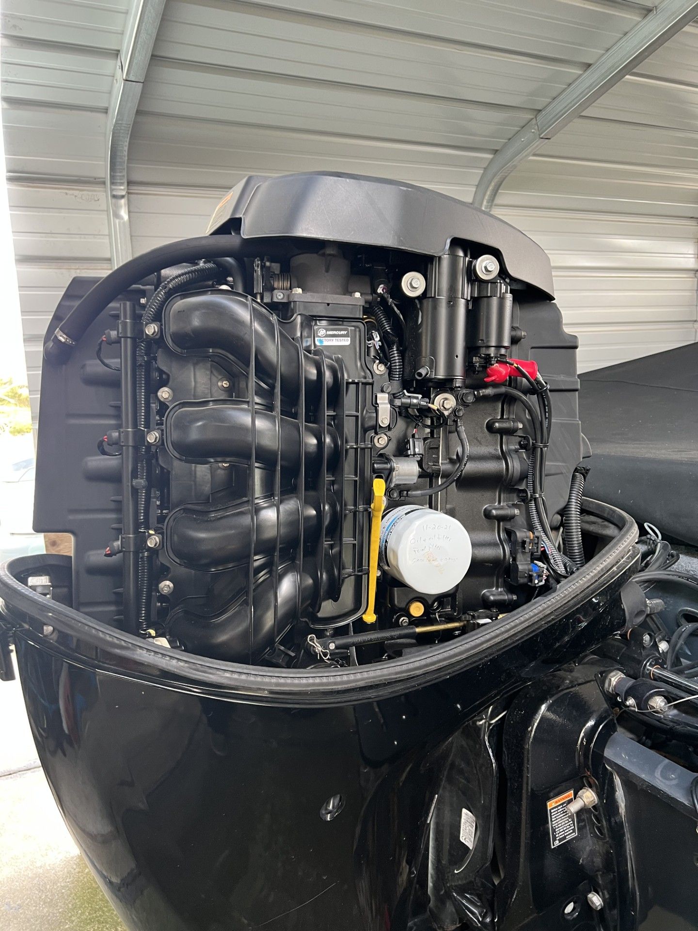 Black outboard boat motor under a metal shelter.