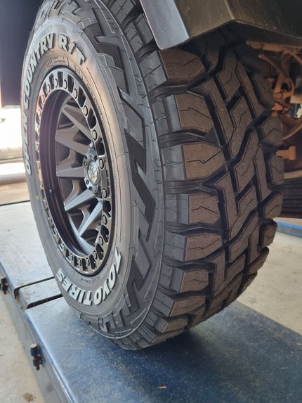 A Man is Holding a Tire in Front of a Car — Turbo's Tyres Pty Ltd In Humpty Doo, NT