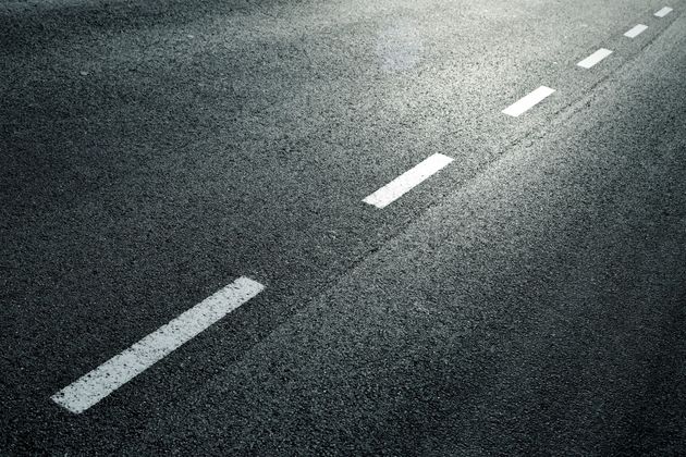 Empty asphalt road with white dashed lane markings