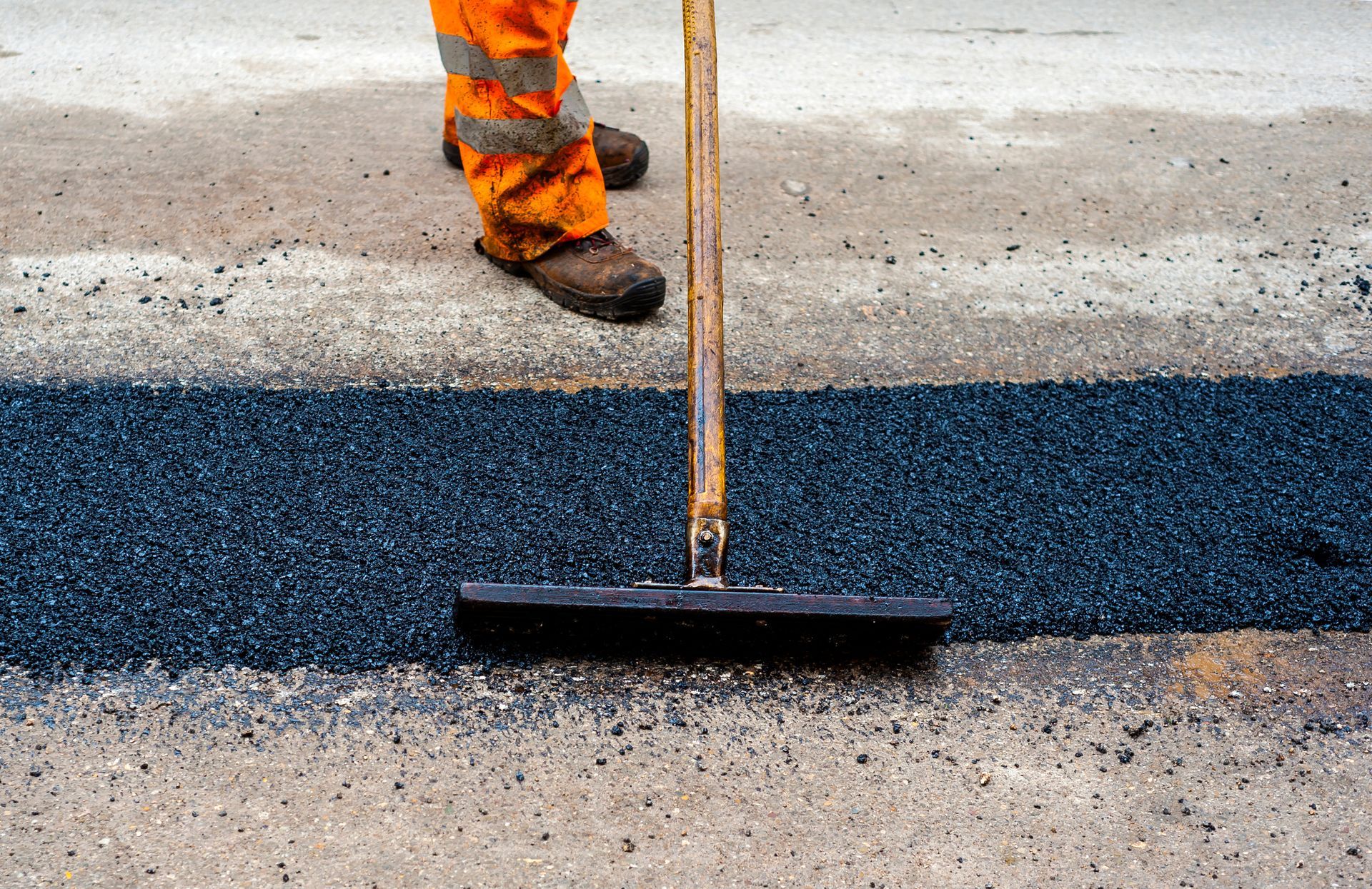 Yellow road roller compacting fresh black asphalt, with steam rising from the road surface