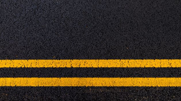 Two yellow horizontal road lines on a dark, speckled surface