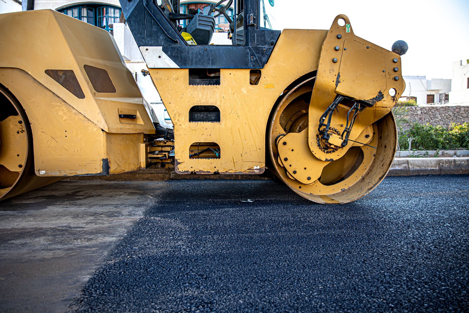 Yellow road roller on freshly paved asphalt at a construction site