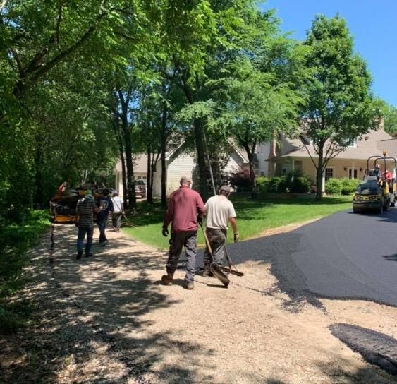 Worker applying sealcoating using a brush to resurface asphalt during a project.