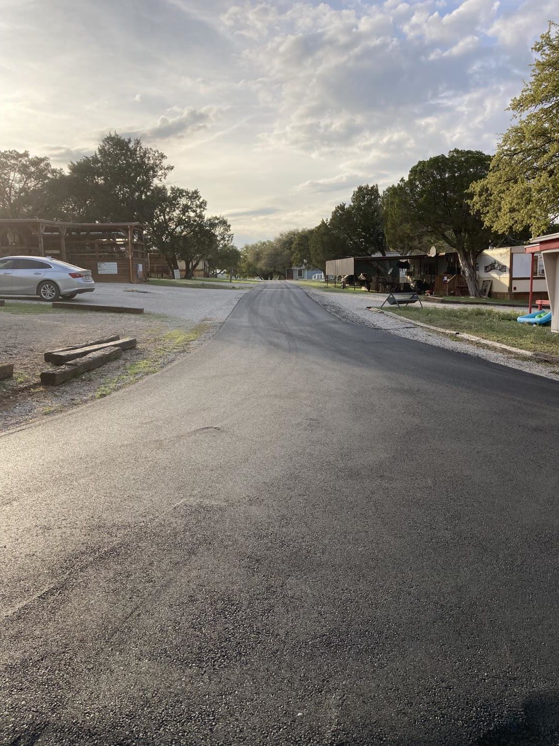 An asphalt driveway leading to a house, featuring a smooth, dark surface with neatly defined edges and a subtle sheen.