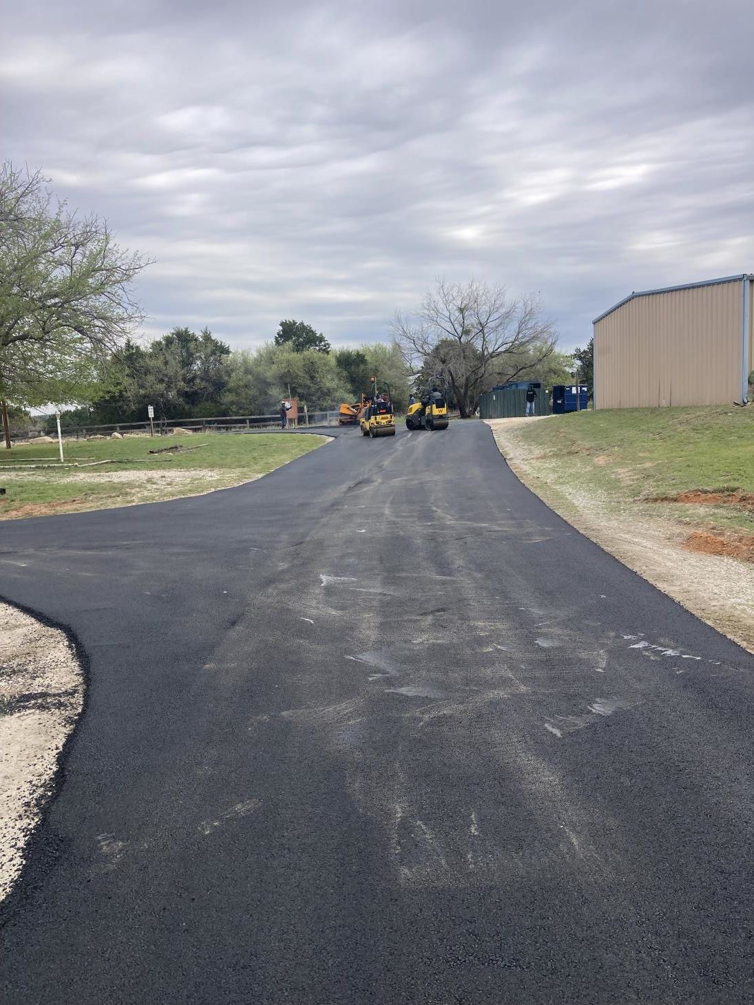 An industrious worker operates a road patcher machine, meticulously repairing cracks on the road surface.