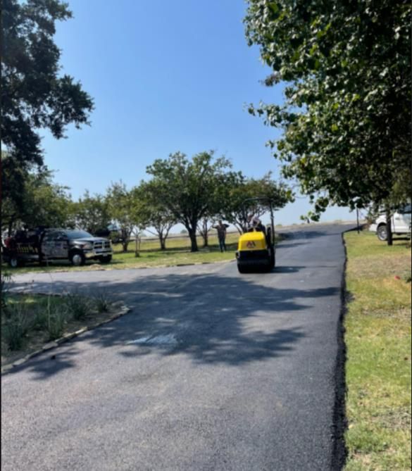 A worker smooths out a fresh layer of blacktop on an asphalt street, repairing damage and improving its surface.