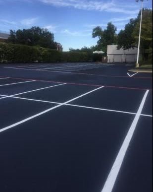 An industrious worker expertly applies a fresh coat of asphalt sealcoating with precision and care, ensuring a smooth and durable surface.