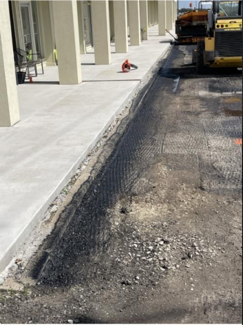 Workers applying blacktop sealer to asphalt street using a spray to provide a protective coat against the elements.