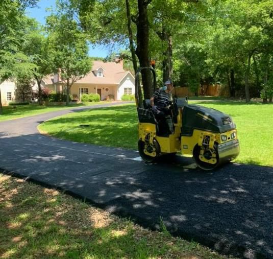 Workers repairing pavement by removing damaged sections and laying fresh asphalt for a smooth and durable road surface.