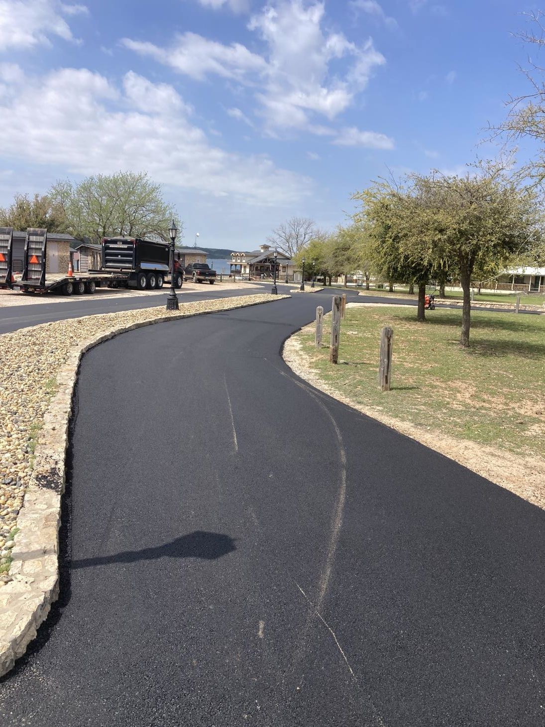 Workers applying blacktop sealer to an asphalt street using a spray, creating a protective coat to guard against weather elements.