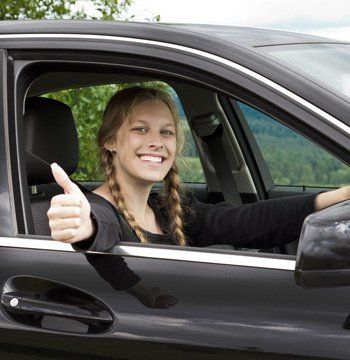 A girl in a car signalling a thumbs up