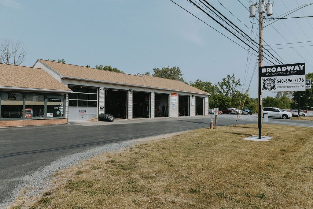 An automotive repair shop with multiple service bays and a sign reading Broadway Automotive alongside a power pole.