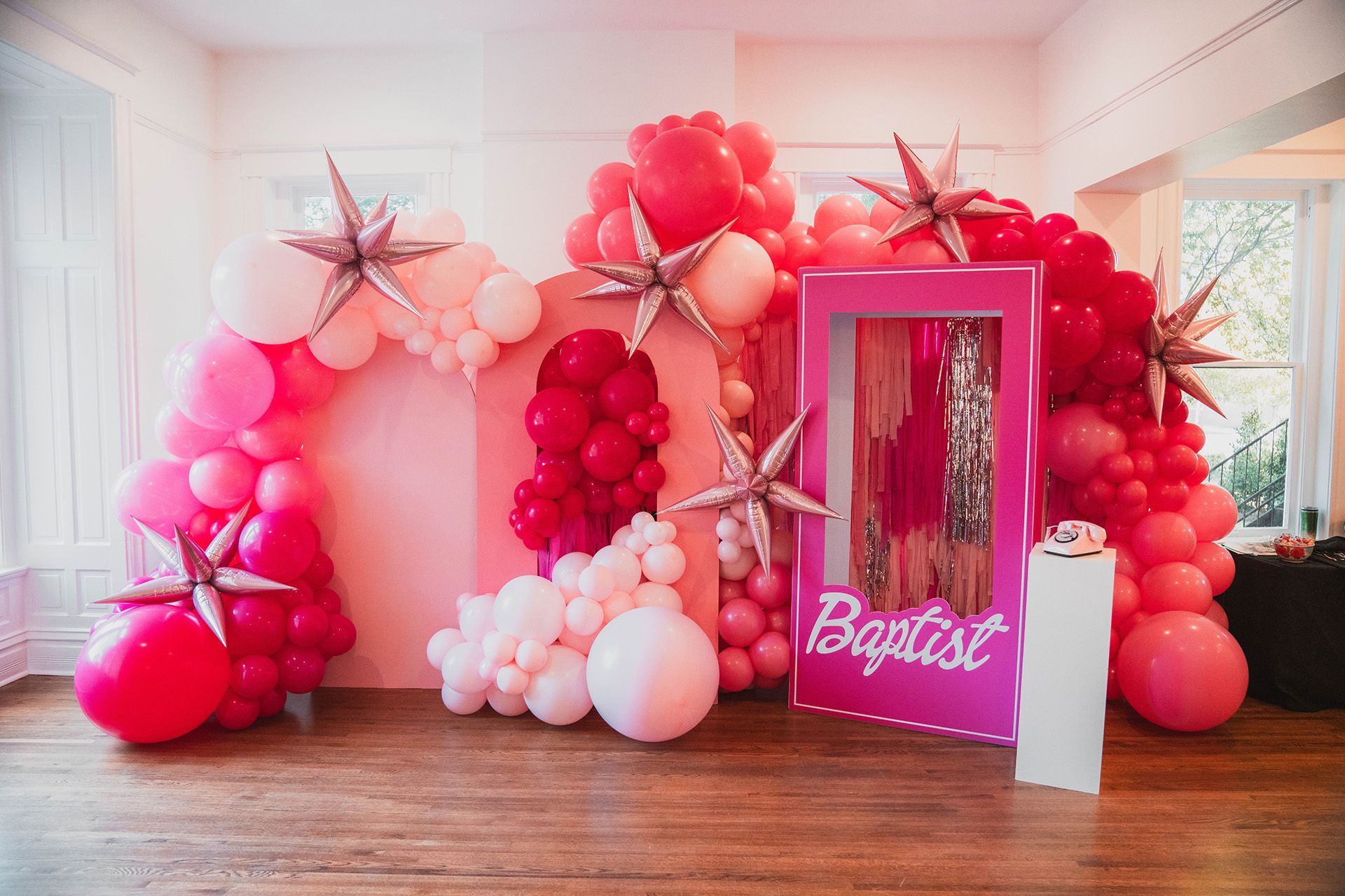 A room decorated with pink and red balloons at a company event