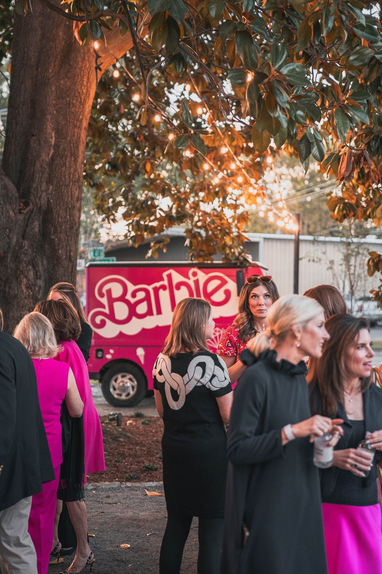 A group of women are standing in front of a barbie truck.