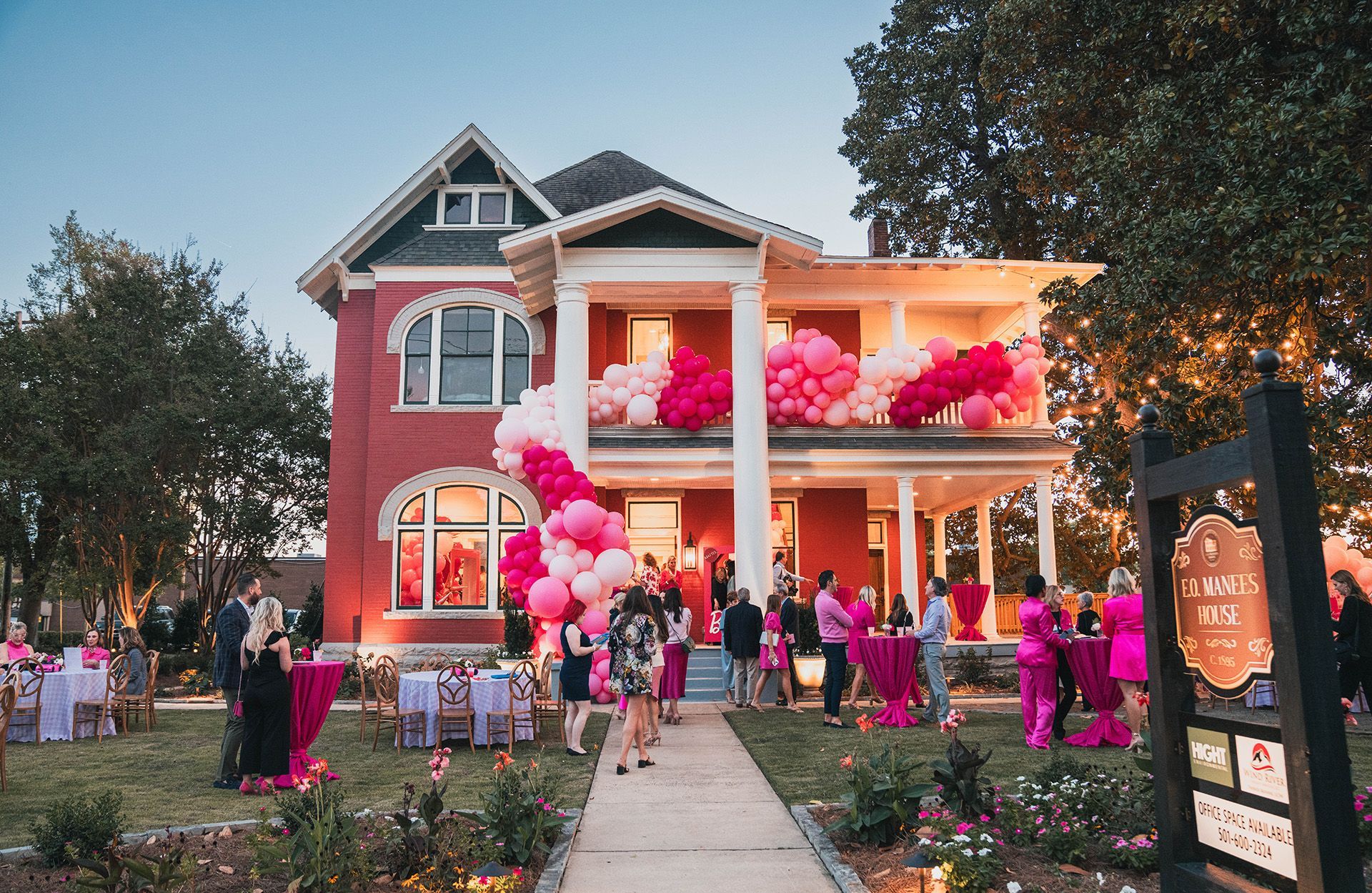 Exterior of E.O. Manees decorated with pink balloons, people gathered in the yard.