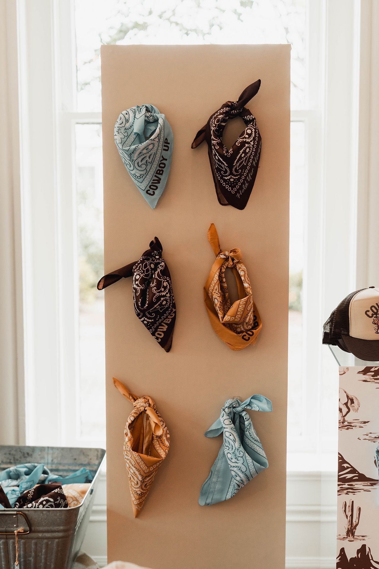 A bunch of bandanas are hanging on a wall.