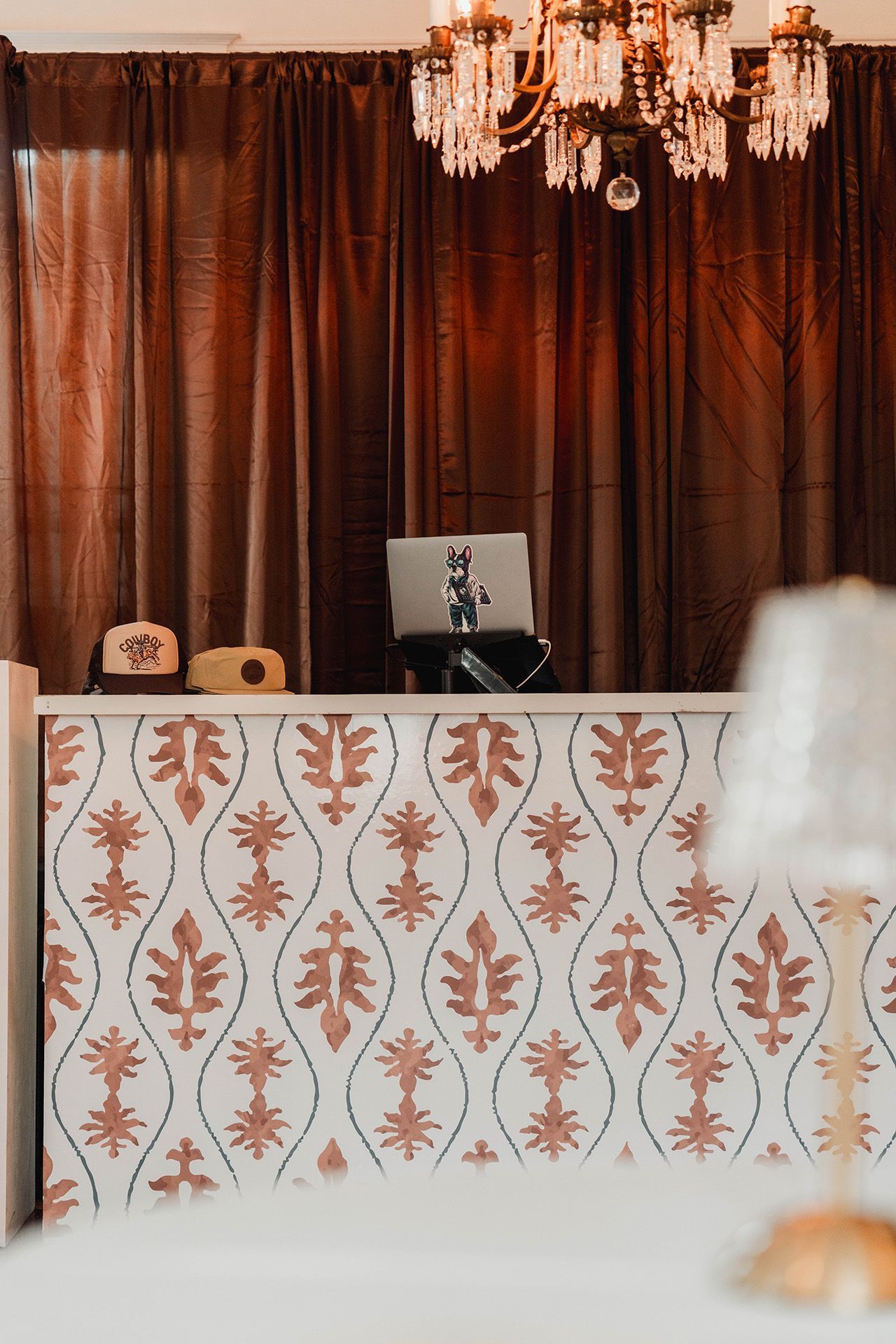 A reception desk with a laptop on it and a chandelier hanging from the ceiling.