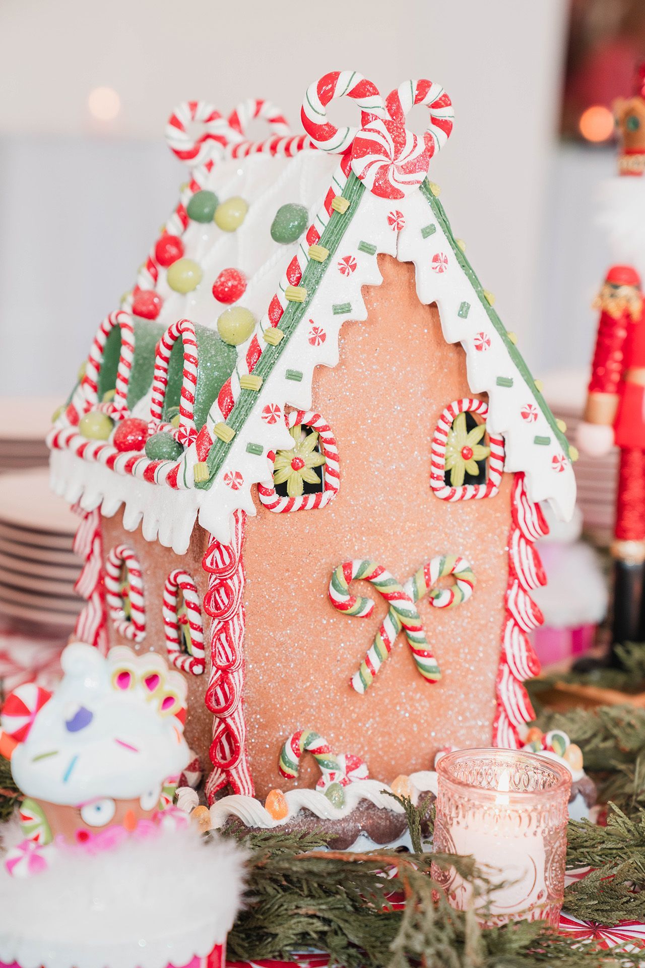 A gingerbread house decorated with candy canes and a candle on a table.