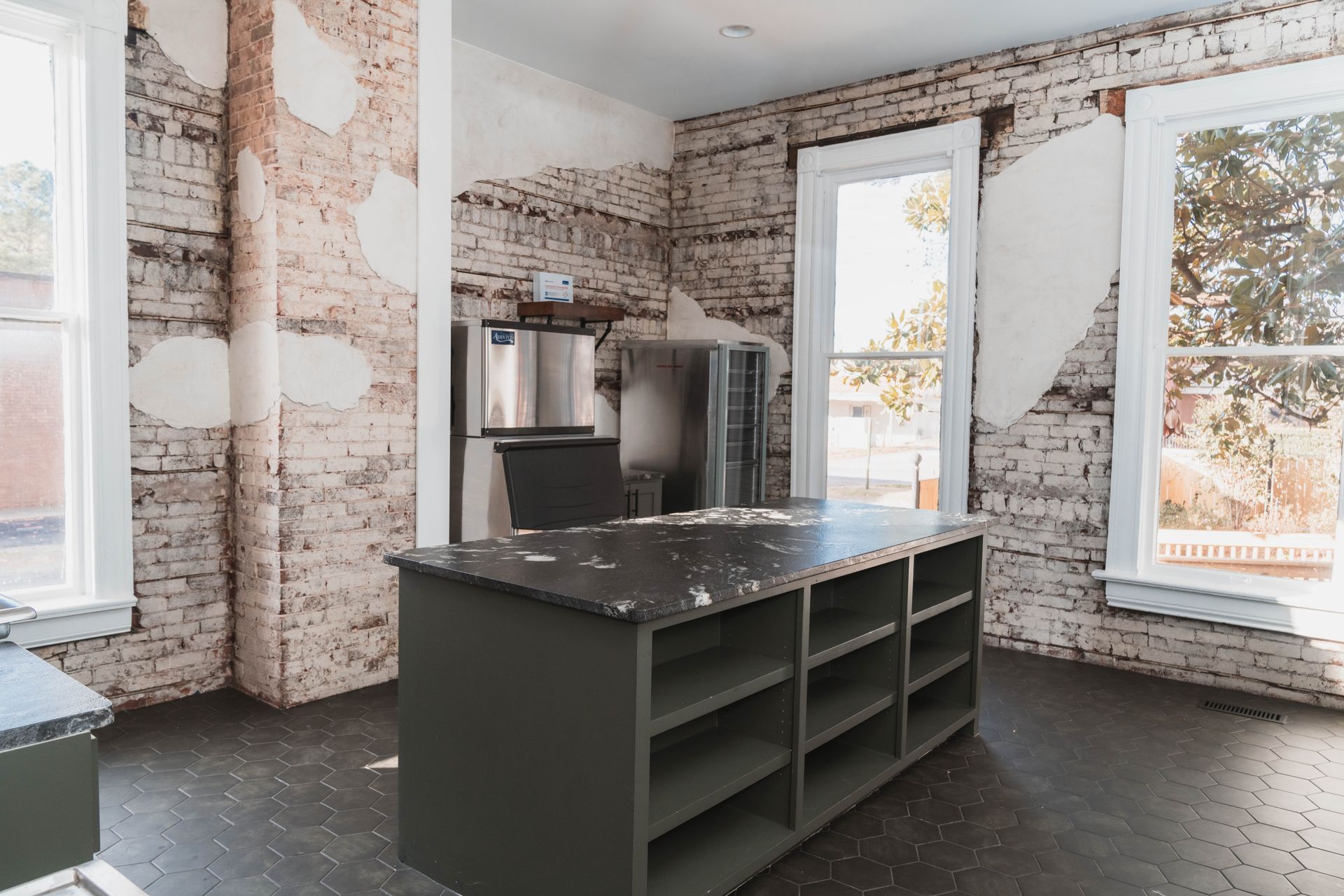 An empty room with a brick wall and a large island in the middle