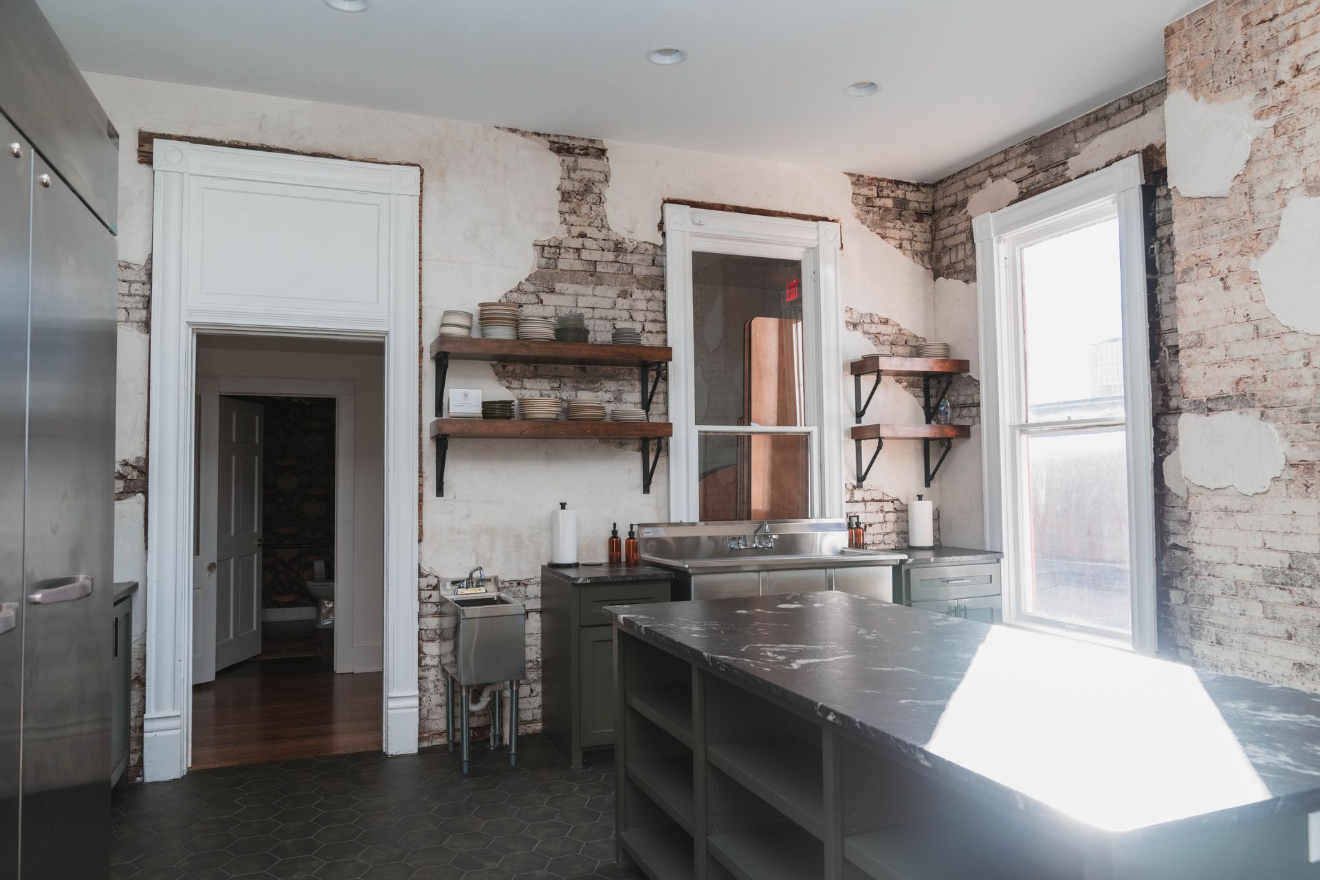 An empty kitchen with a sink , shelves , and a window.