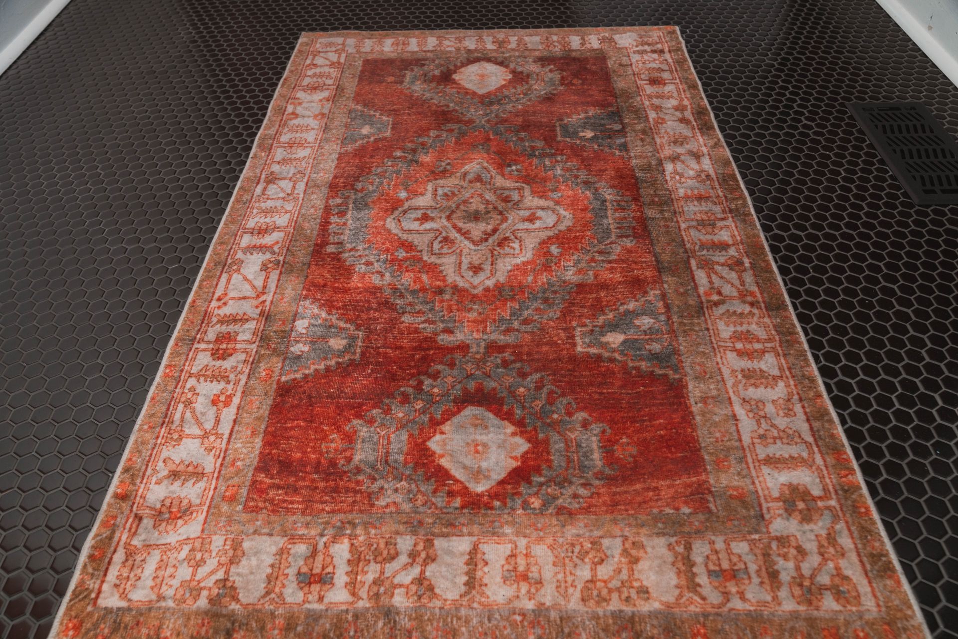 A red rug is sitting on a black tiled floor.