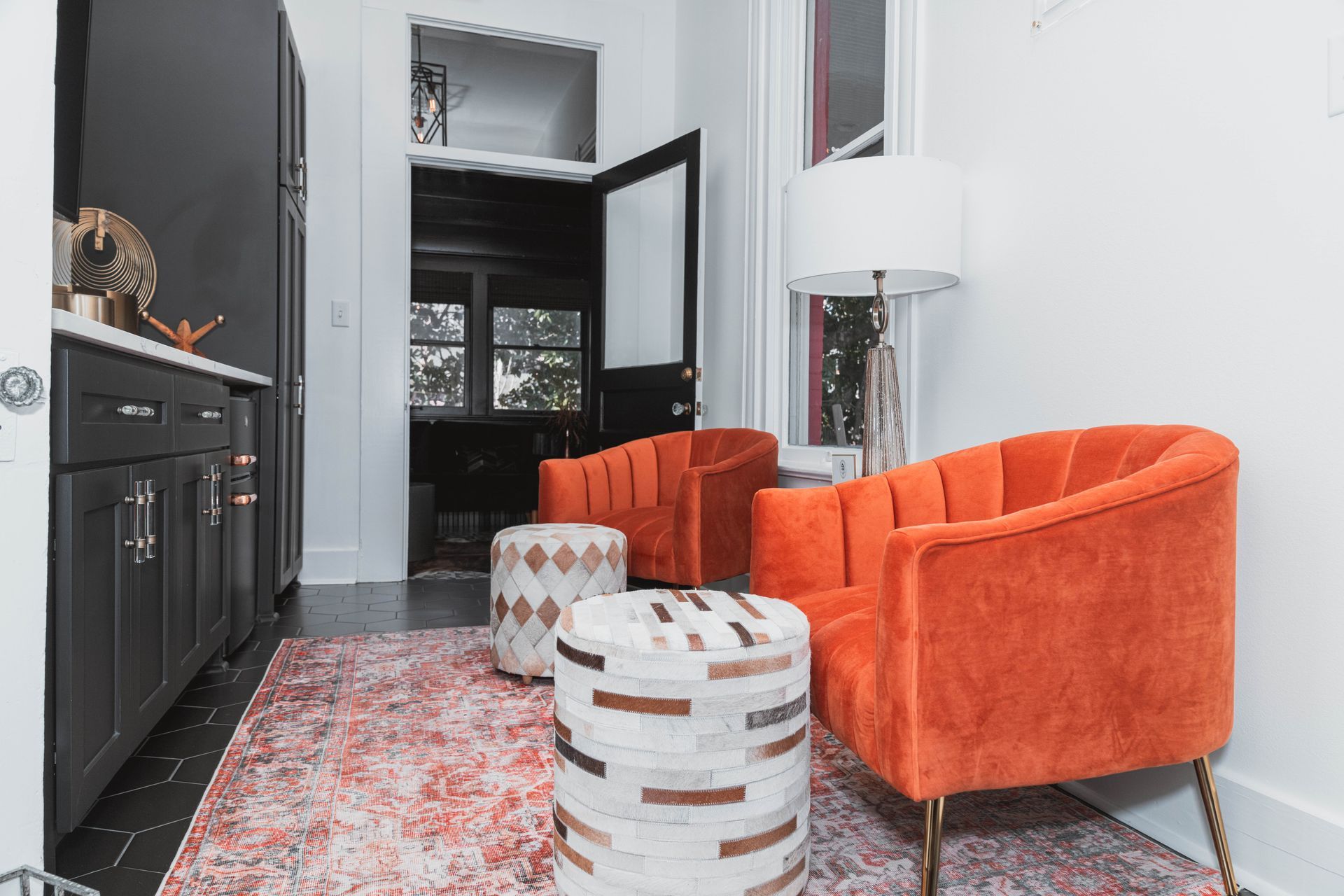 A living room with two orange chairs and two ottomans.