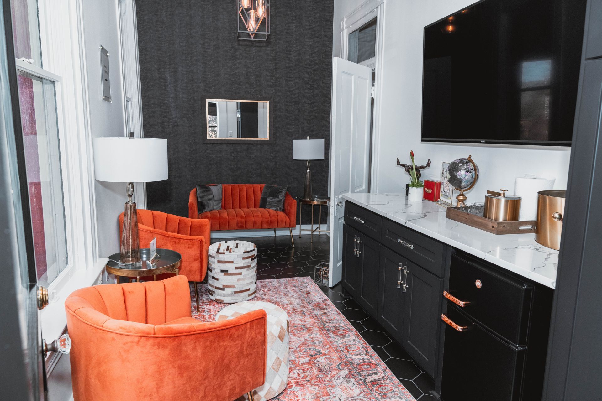 A living room with a couch , chairs , and a flat screen tv.