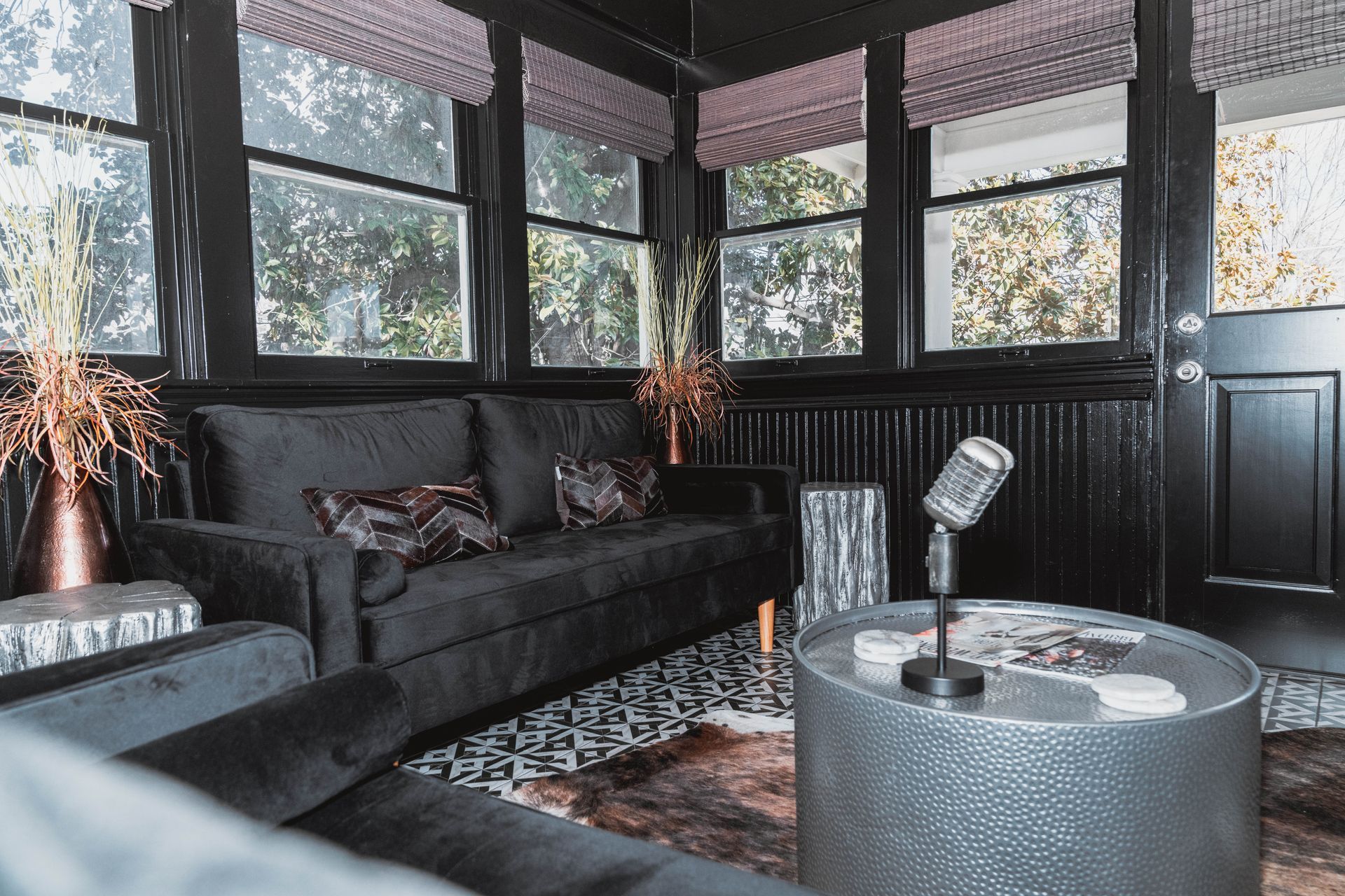 A living room with a couch , chairs , a table and a microphone.