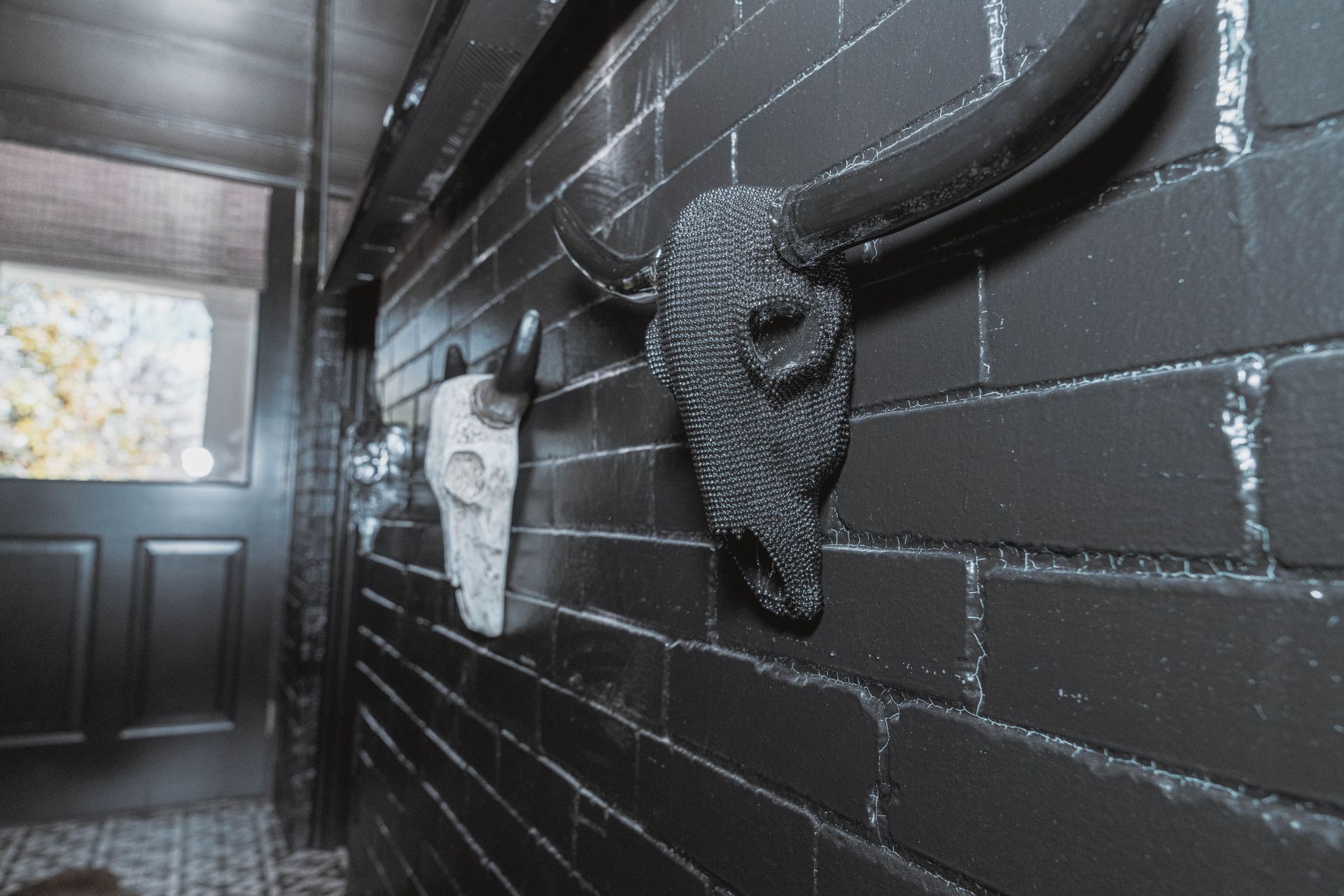 Two bull skulls are hanging on a black brick wall.
